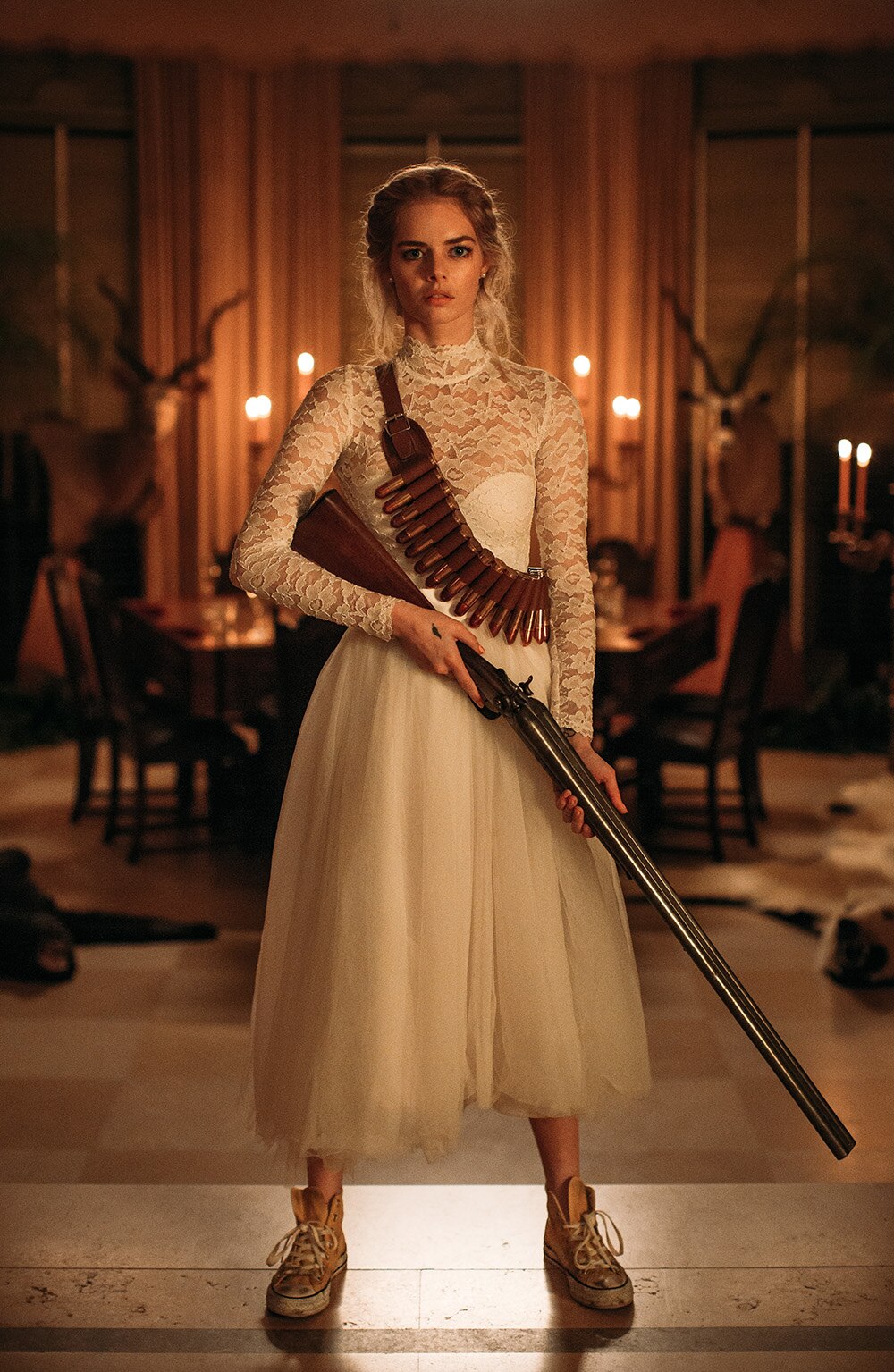 Samara Weaving stands in candlelit room wearing lace wedding dress with cartridge belt slung over shoulder and holding shotgun.