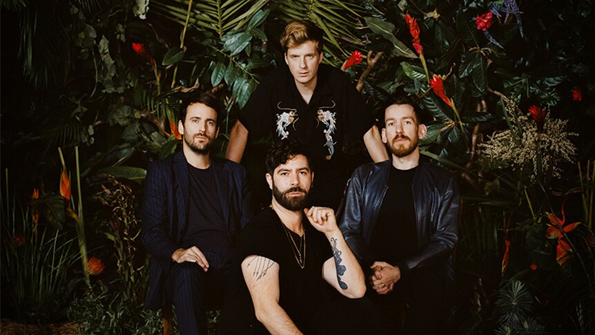The band Foals pose in front of lush jungle plants