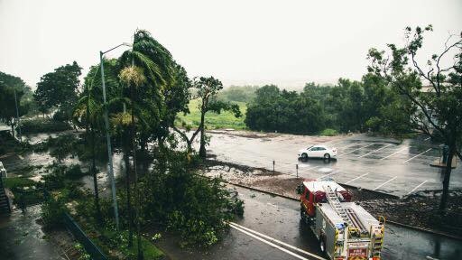 A fire truck parks next to fallen trees on McMinn Street in Darwin, blocking the road.