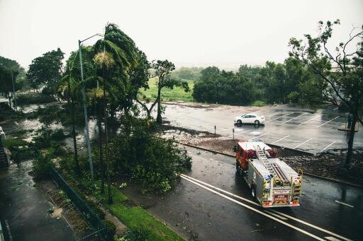 A fire truck parks next to fallen trees on McMinn Street in Darwin, blocking the road.