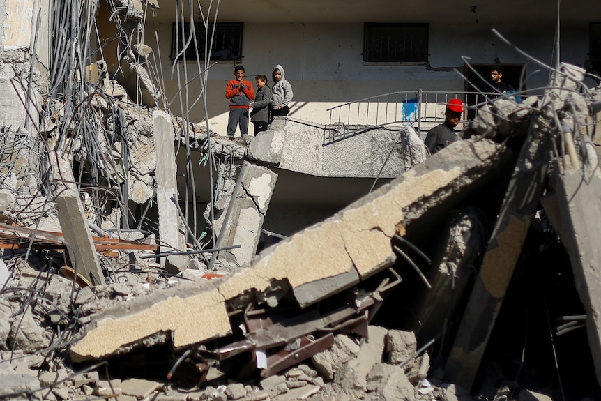 Children are pictured on the rubble on a building. 