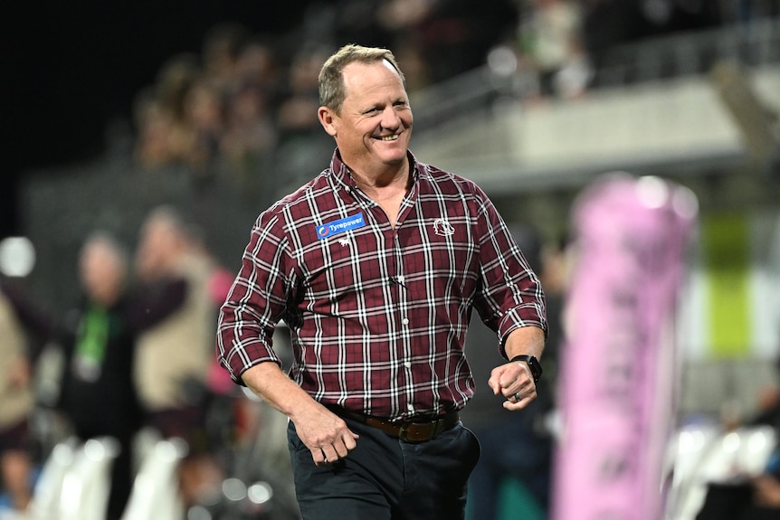 kevin walters walks along a stadium football field sideline smiling