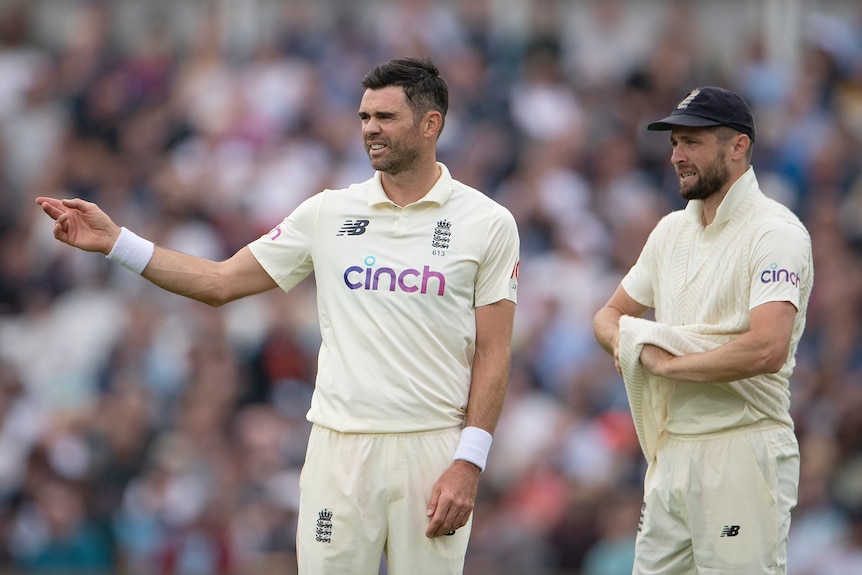 James Anderson points to one side standing next to Chris Woakes