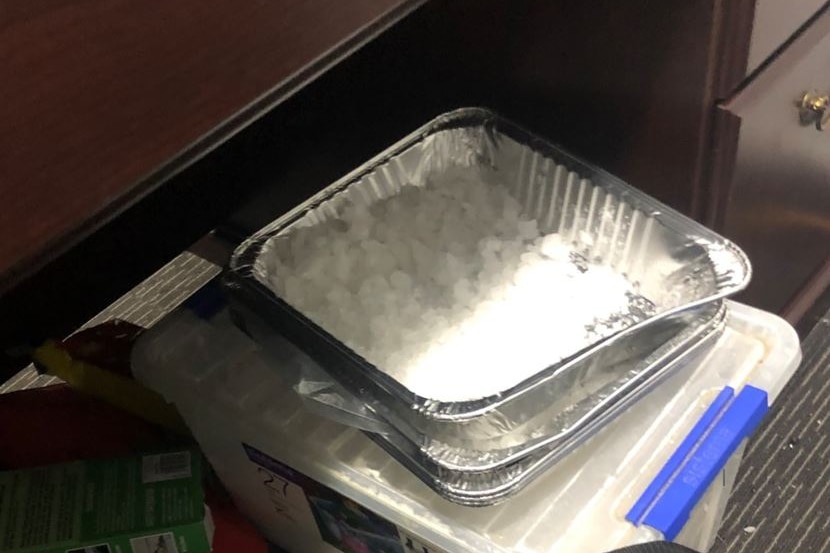 Drugs sit in an aluminium tray underneath a desk.
