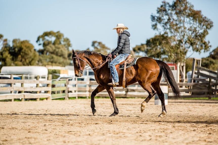 woman riding a horse with a plush jacket on and a hat, jeans too