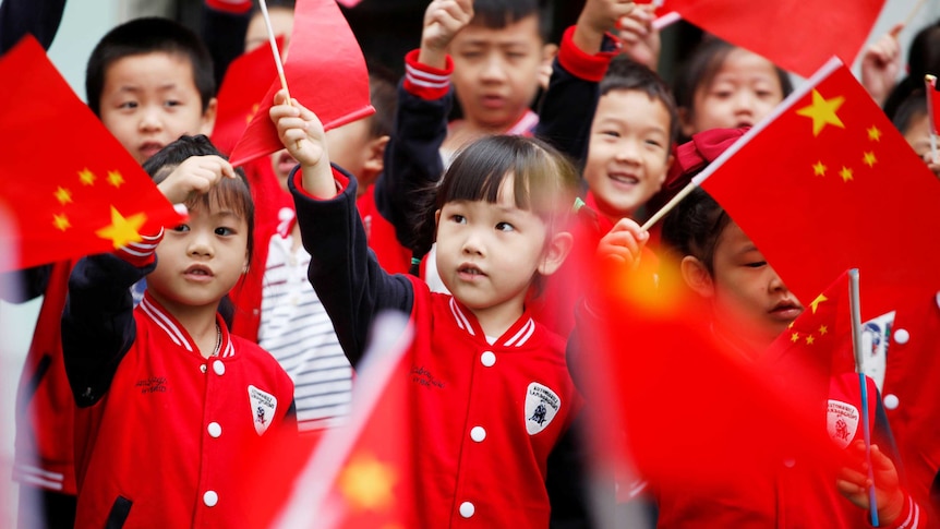 Little children waving a bunch of Chinese flags