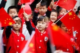 Little children waving a bunch of Chinese flags