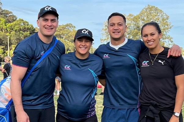 Two men and two women stand next to each other, arms around each other, smiling