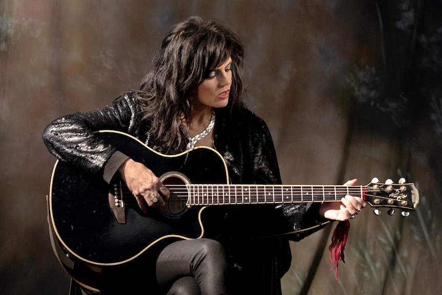 Performer Wendy Rule plays a guitar.