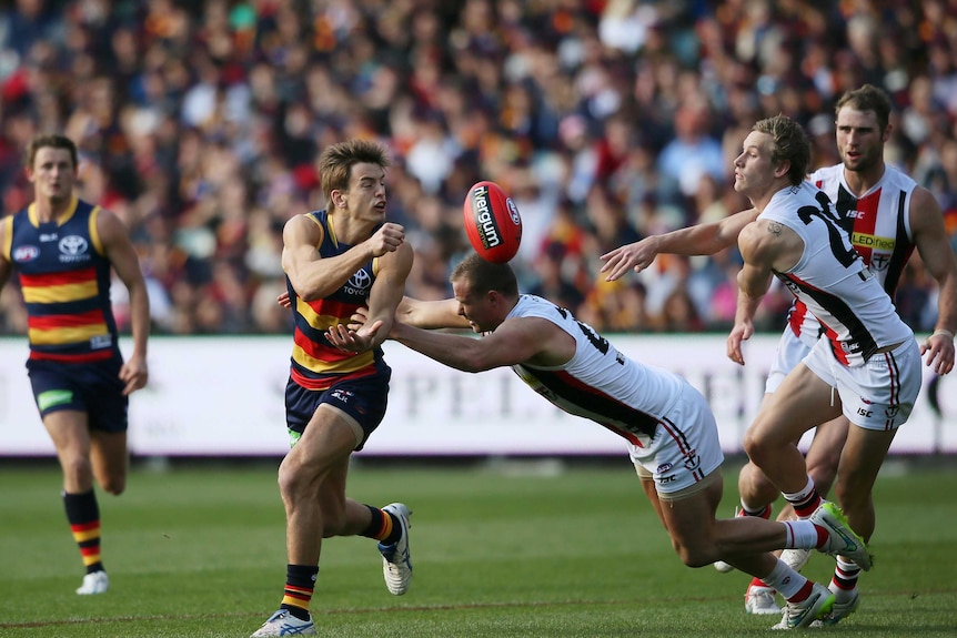 Jarryd Lyons of the Adelaide Crows gets a hand ball away.