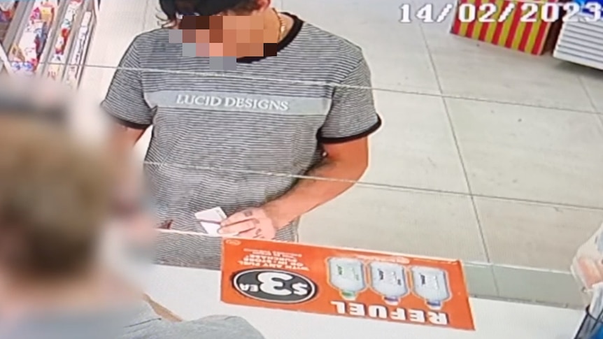 A man at a service station counter with blurred face.