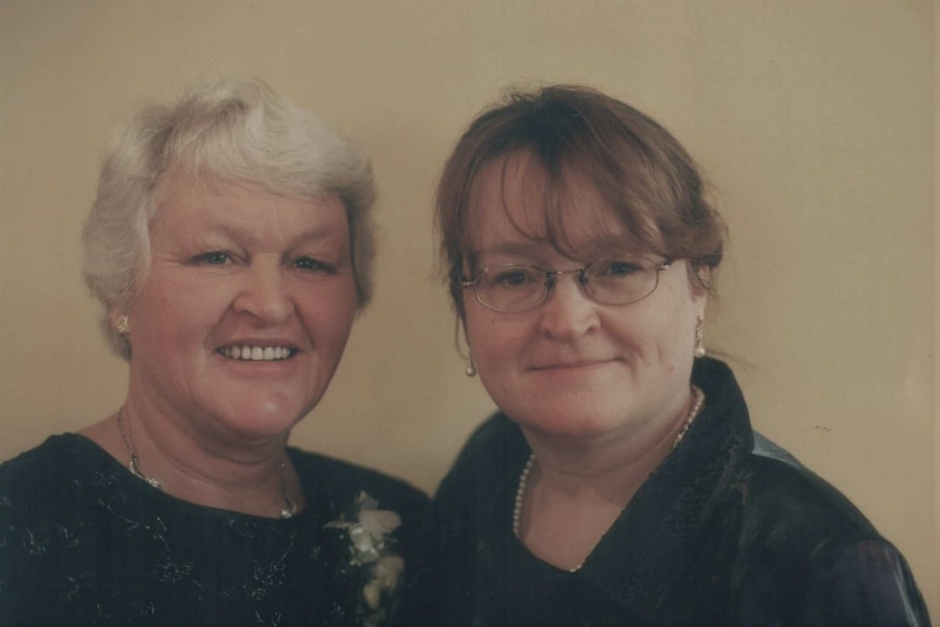 Two women, one slightly older than the other, smile softly at the camera.