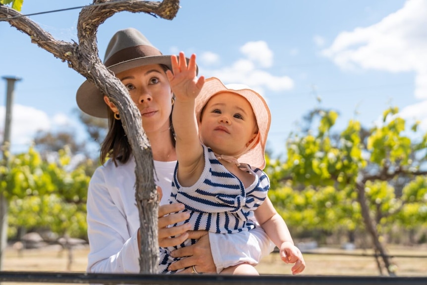 a mother and daughter wearing hats are out in a vineyard