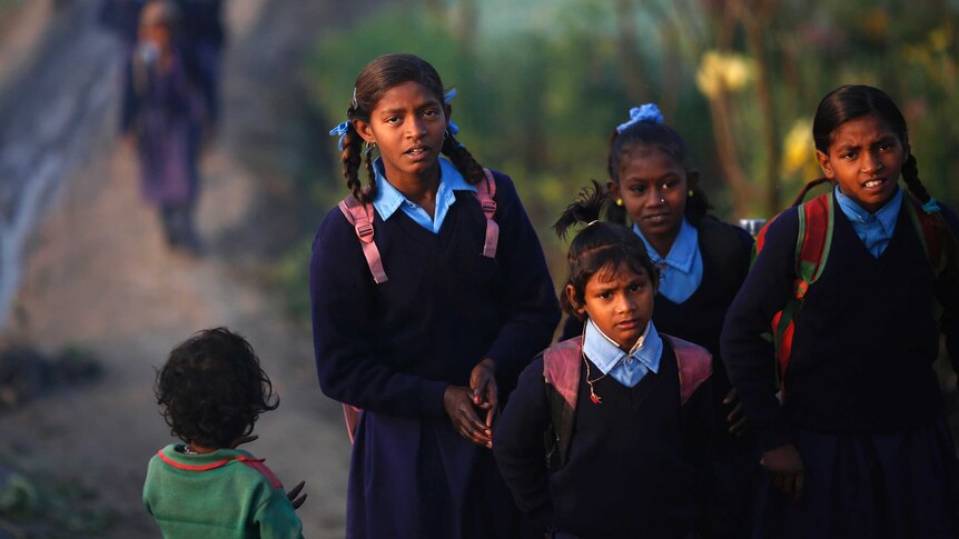 Schoolgirls make their way to their school through a vegetable field in New Delhi.