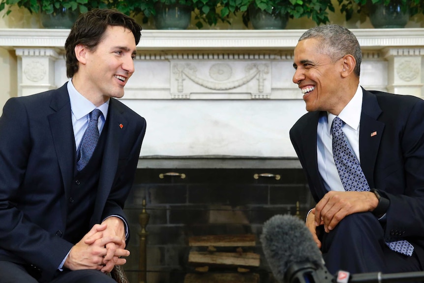 Justin Trudeau and Barack Obama, both seated, look at each other and share a laugh during a meeting in the Oval Office.