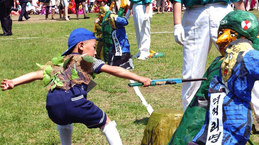 A North Korean child stabs an effigy of a US soldier with a wooden toy rifle during a game.