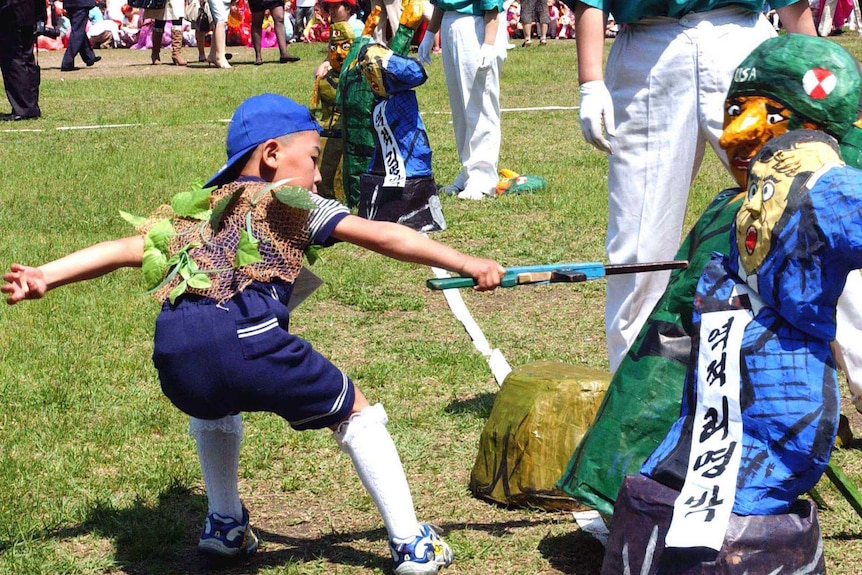 A North Korean child stabs an effigy of a US soldier with a wooden toy rifle during a game.