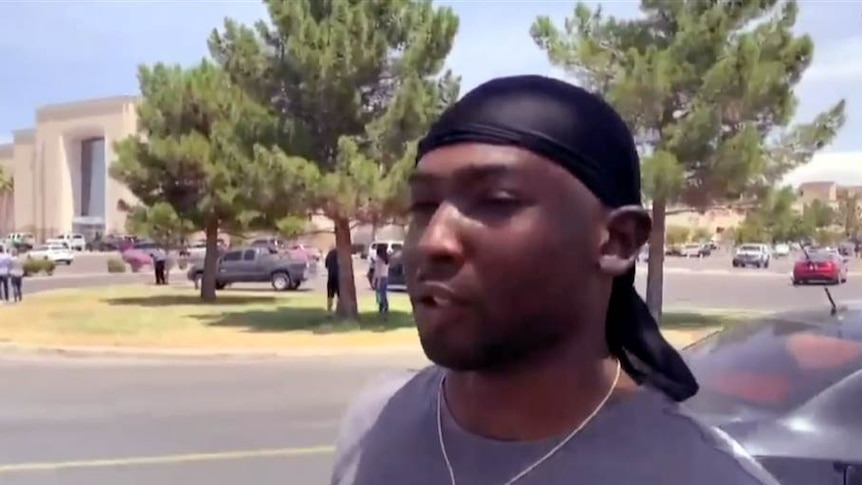 A man wearing a durag speaks to reporters in a carpark