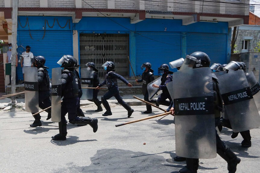Nepalese police in riot gear are armed with sticks and shields.