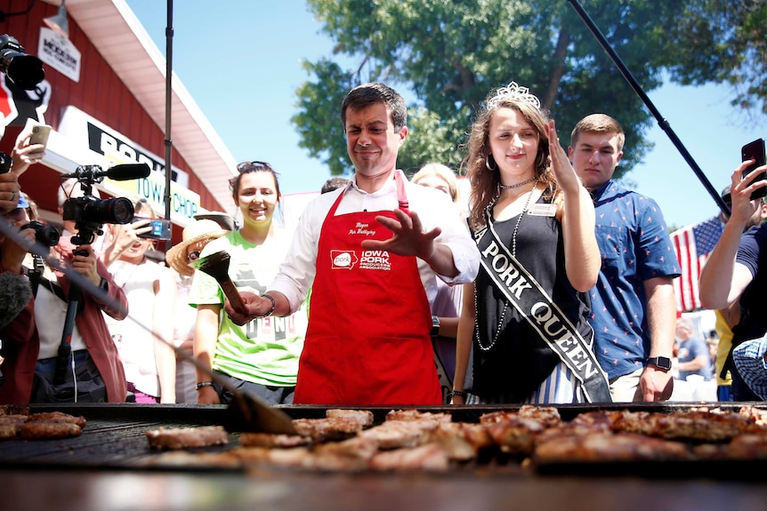 Pete Buttigieg stepping back from a barbeque grill surrounded by people