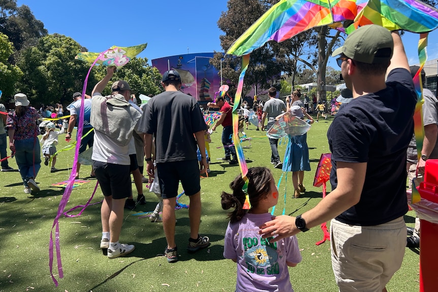 Children fly kites in a park on a sunny day.