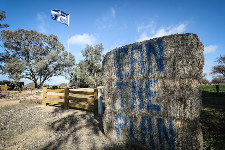 Three hay bales are stacked with the words "Can the Plan" spray painted on them, and the Eureka flag flies beside.