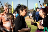 An Indigenous woman gathers at a memorial in a suburban park. 
