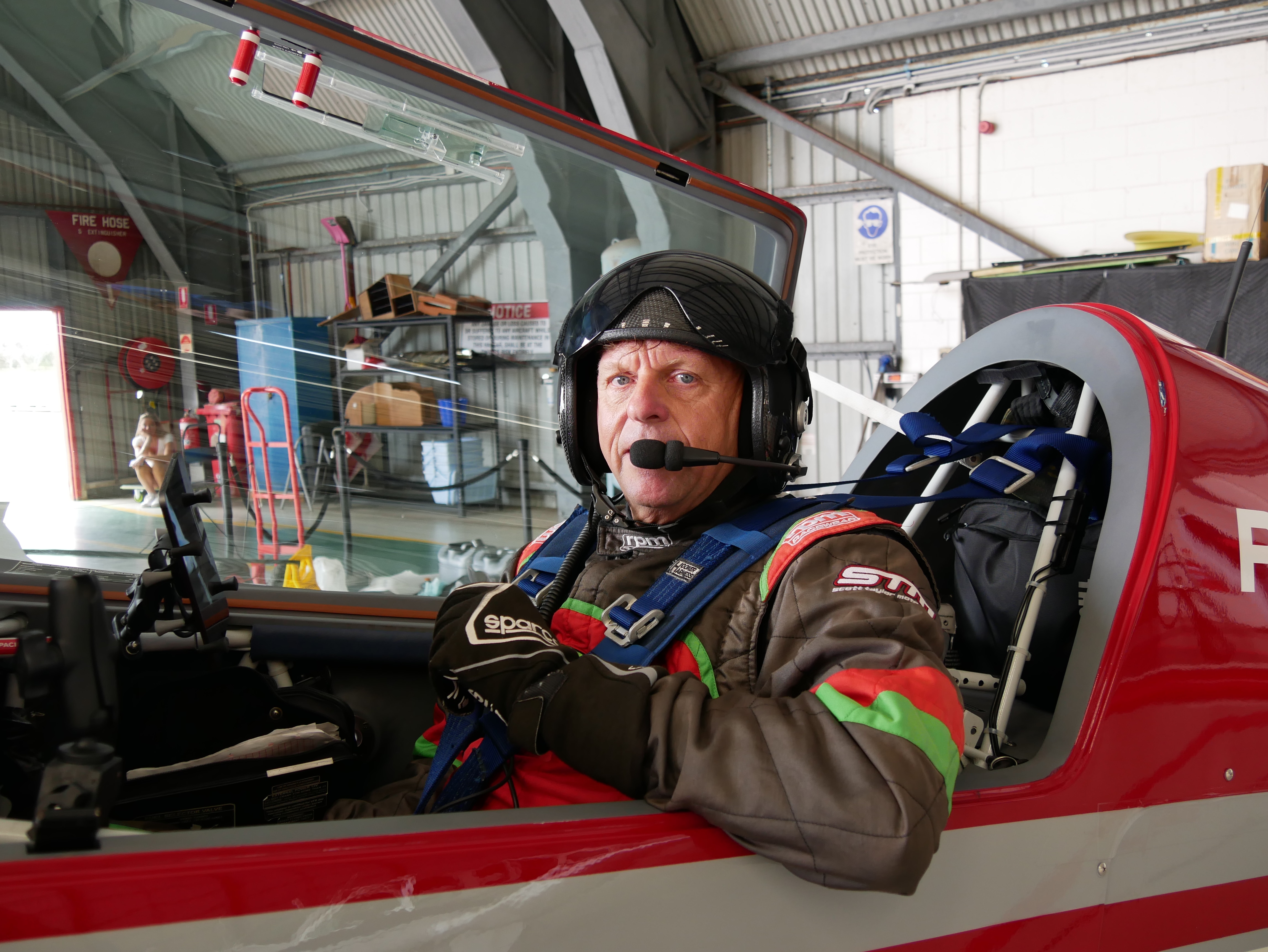 Man smiles from the cockpit of small plane.