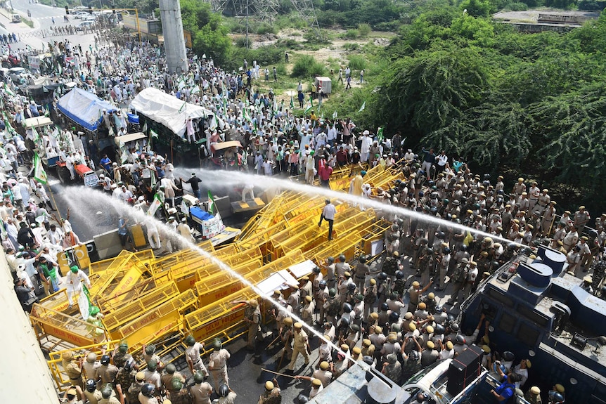 An aerial shot of police water bombing hundreds of protestors trying to get through yellow barricades