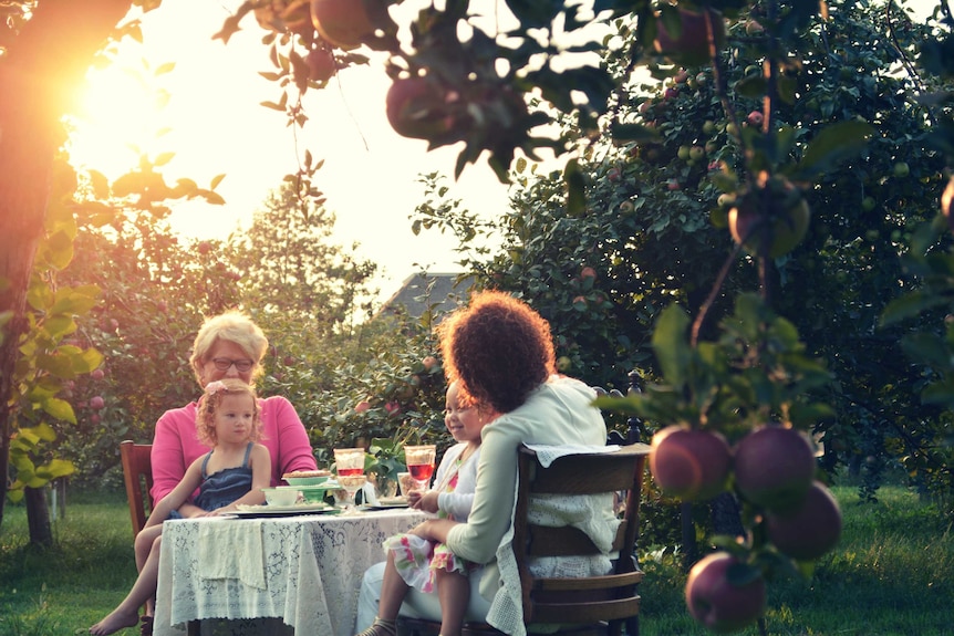 Women in the garden with young children having lunch