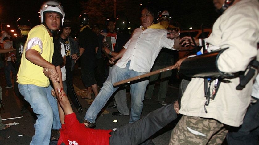 A government supporter is kicked by an anti-government demonstrator in Bangkok