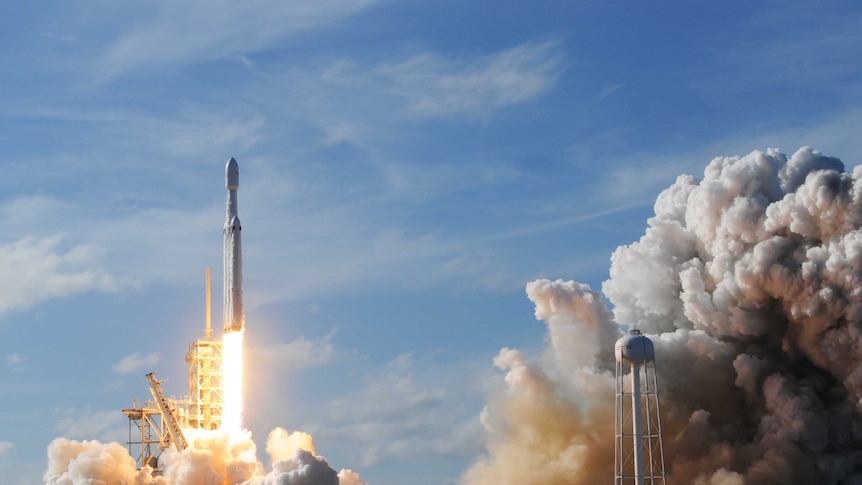 The SpaceX Falcon Heavy rocket launches in a cloud of smoke.