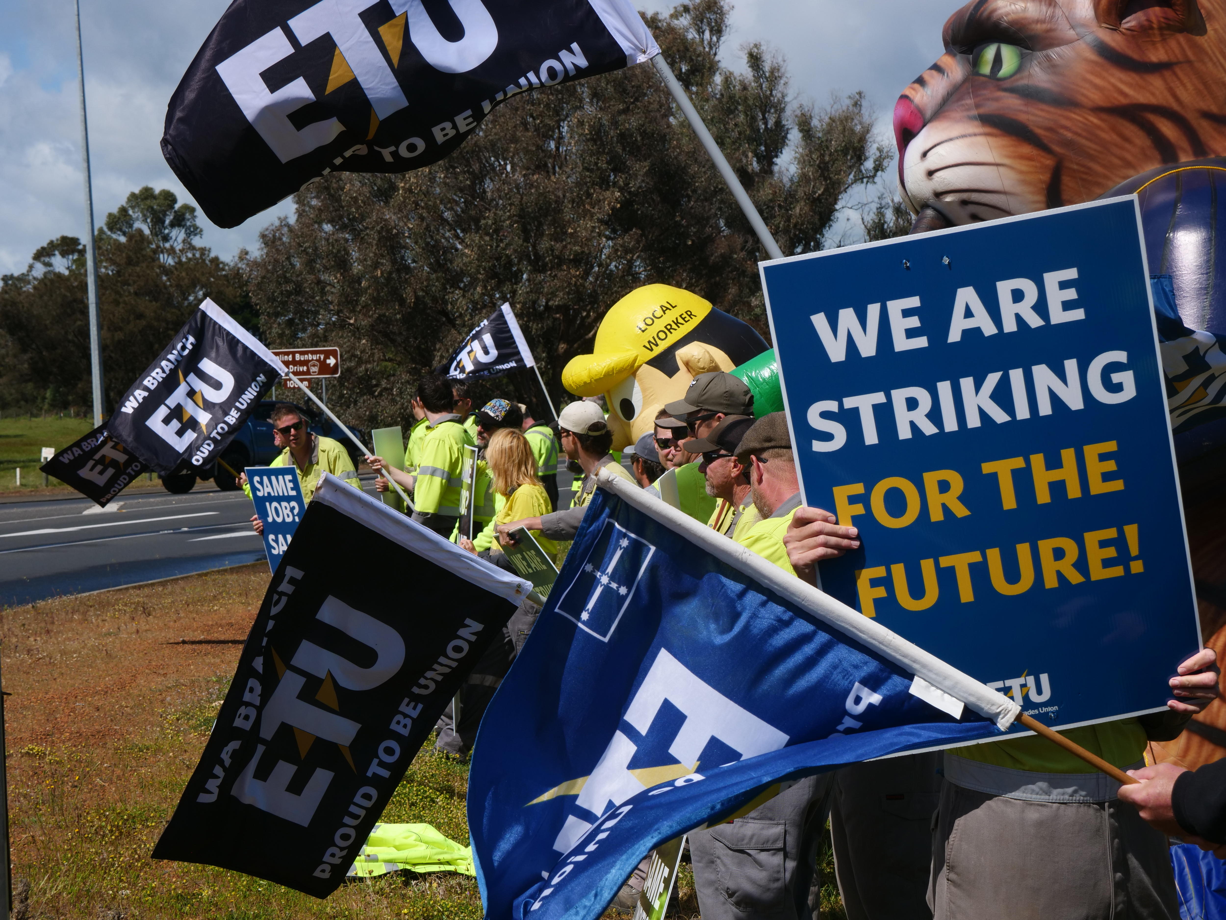 Workers flying protest and union flags during a stop work meeting.