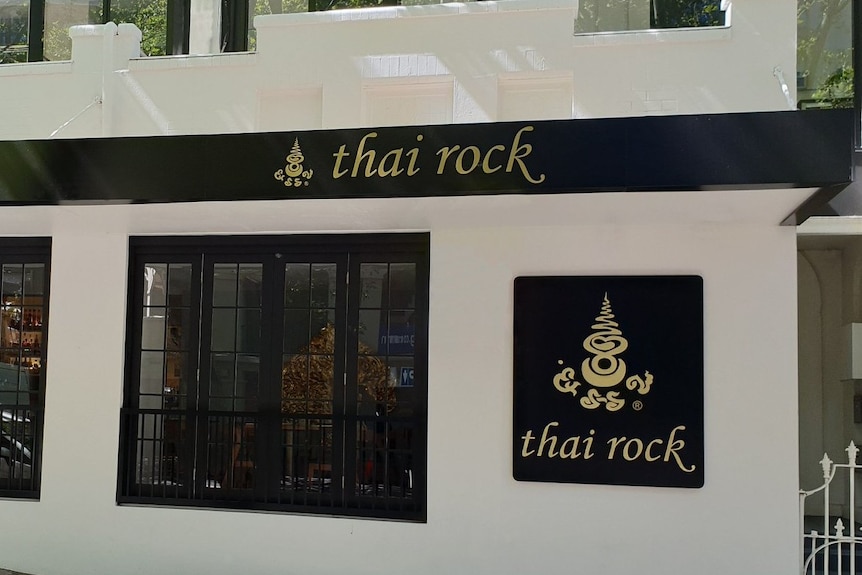 A building with the words Thai Rock on the front and a tree on the footpath.