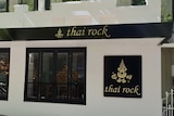 A building with the words Thai Rock on the front and a tree on the footpath.
