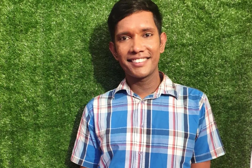 Shaheel Prasad poses for a photo against a green background. 