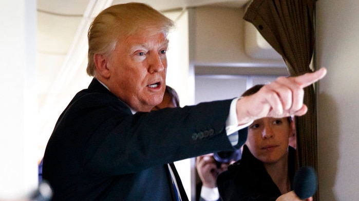 US President Donald Trump points as he speaks with reporters on Air Force One.