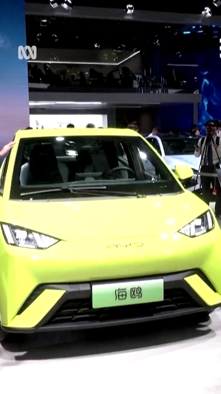 A yellow car with Chinese characters on the display plates sits under artificial lights indoors