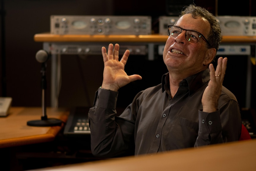 Lucky Oceans with his hands in the air as he is interviewed in a music studio.