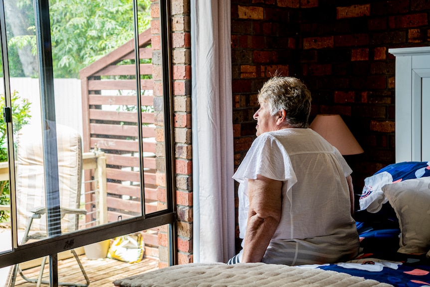 An older woman looking out of a window.