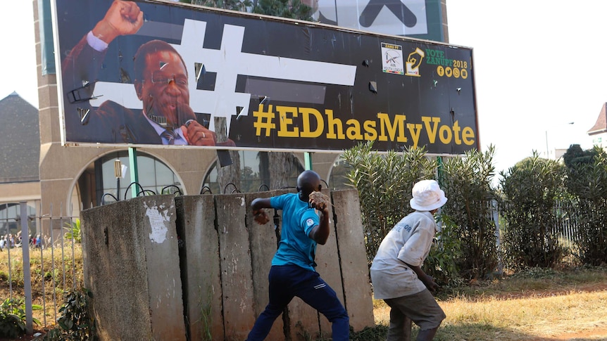 An opposition party supporter throws a rock aimed at Zimbabwean President Emmerson Mnangagwa's election campaign poster