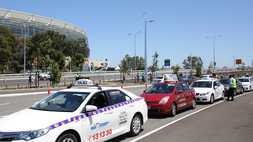 Taxis lined up on a road outside Perth Stadium.