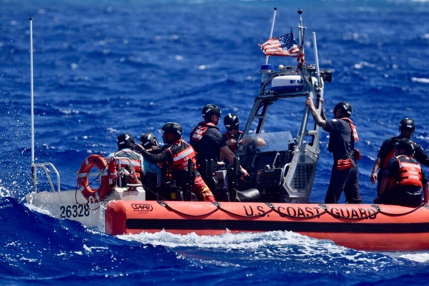 A coast guard boat full of staff and three men who have just been rescued.