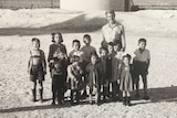 A young school teacher standing with students in 1954