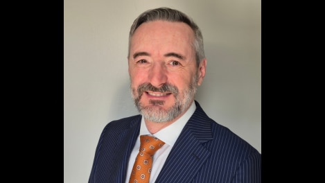 A middle-aged, bearded man in a suit.
