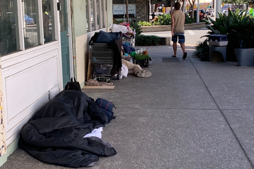 Two men sleeping in sleeping bags on a street