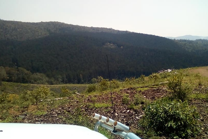 The bonnet of a four-wheel-drive, overlooking scrubland with mountains in the background.