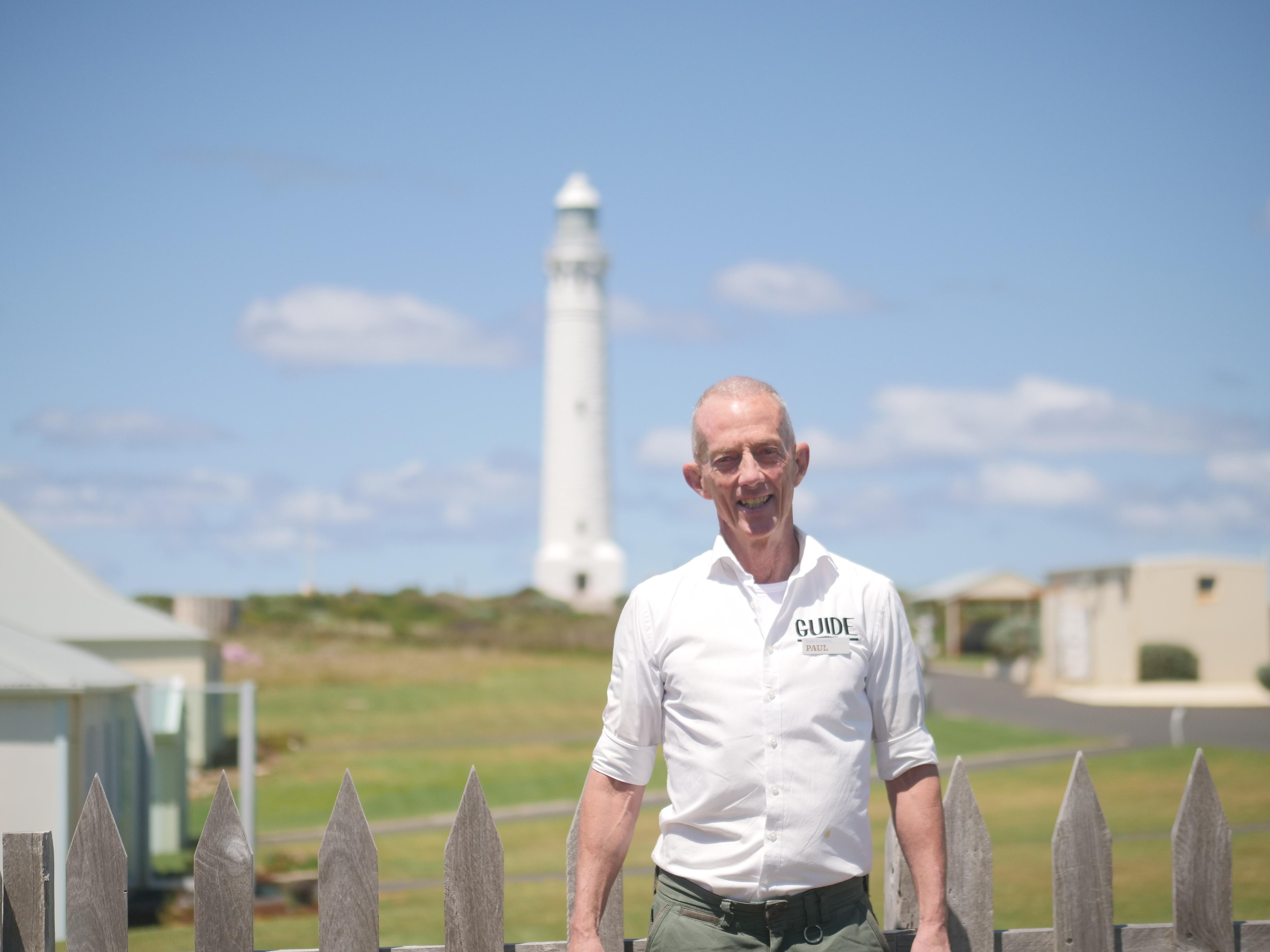 A man standing in front of a lighthouse.