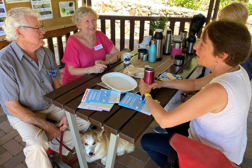 Four adults sit around a picnic table