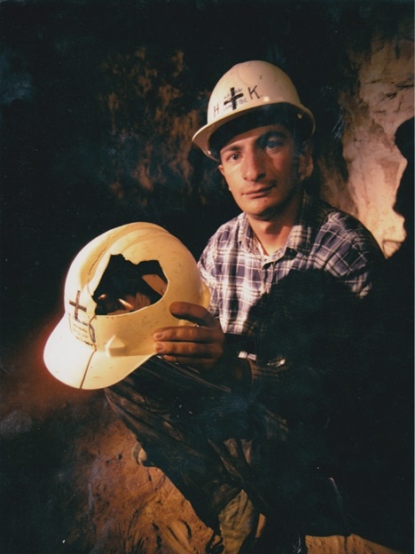 Ilias Katsapouikidis sits in mine shaft holding smashed helmet